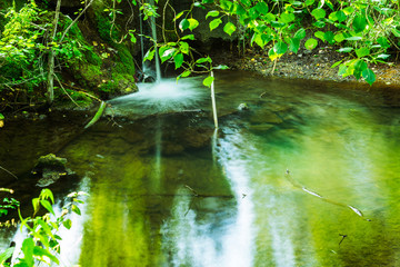 Small artificial waterfall on the forest river. Long exposure.