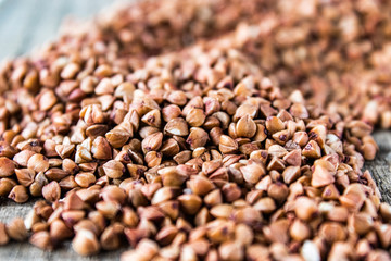 A pile of uncooked buckwheat scattered on old boards. Buckwheat is used for cooking.