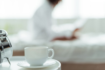 selective focus of cup of coffee and saucer in bedroom at morning