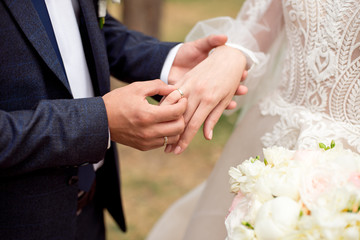 Obraz na płótnie Canvas Groom wears bride a wedding ring Bride hand holds a beautiful wedding bouquet