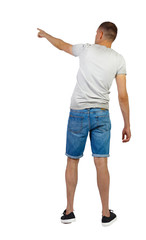Back view of going handsome man in shorts pointing.