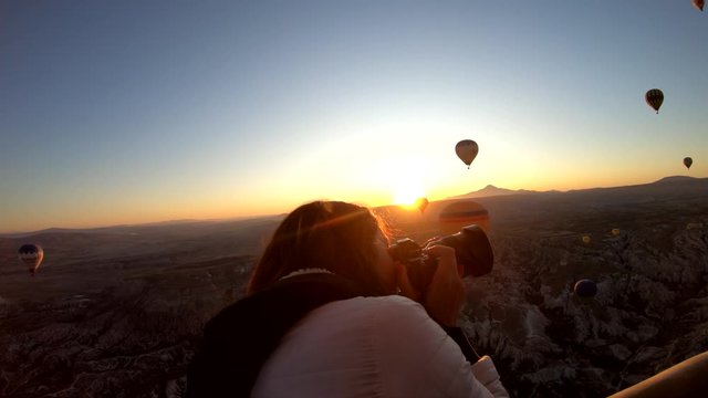 Girl taking pictures in hot air balloon at sunrise, Cappadocia, Turkey