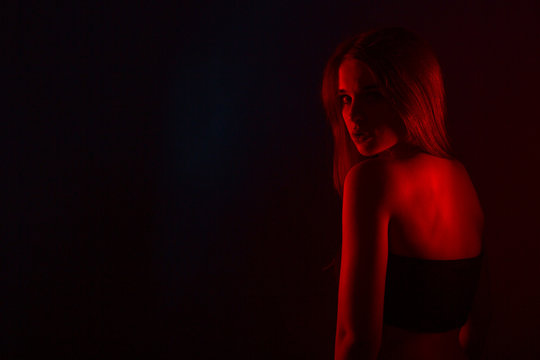 Young beautiful woman in lingerie posing in red back light