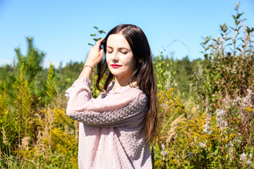 Beautiful brunette woman with red lips on the field in the summer