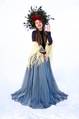 Fototapeta premium young stylish girl in dress with long hair and crown of christmas trees and berries on the head is standing and smiling happy on white background. christmas new year concept, free space
