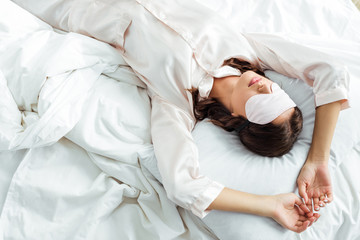 top view of woman in sleeping mask lying in bed at morning