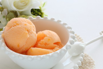 Orange ice cream in white bowl with copy space