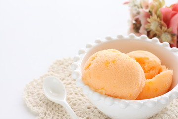 Orange ice cream in white bowl with copy space