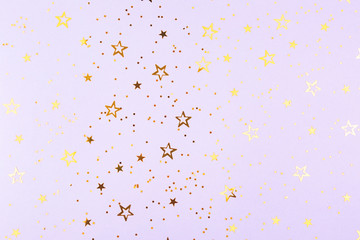 Falling golden stars confetti on purple background. Flat lay, top view. Copy space.