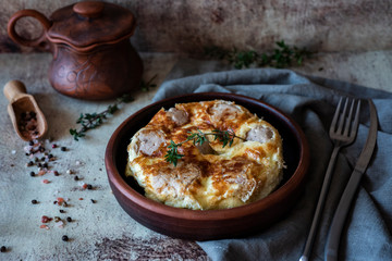 Appetizing omelet with meat meatballs on a clay plate on an ancient gray background