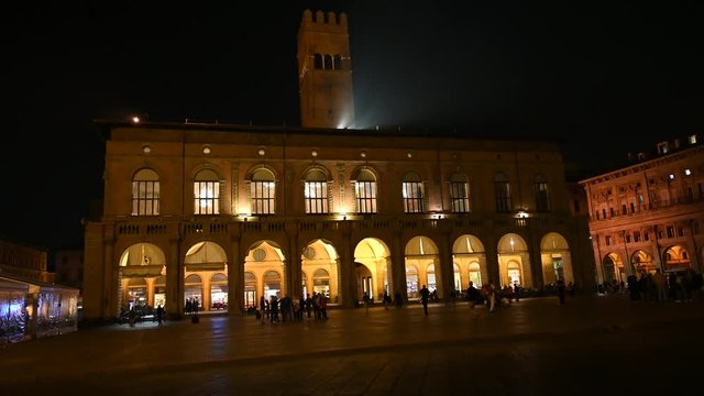 Bologna, Italy - October 2019 - Unknown people walk in the evening among the buildings and monuments of the historic city center, followed by the shadows of the night