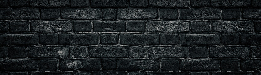 Black rough brick wall close-up wide texture. Old dark masonry panorama. Gloomy grunge widescreen background