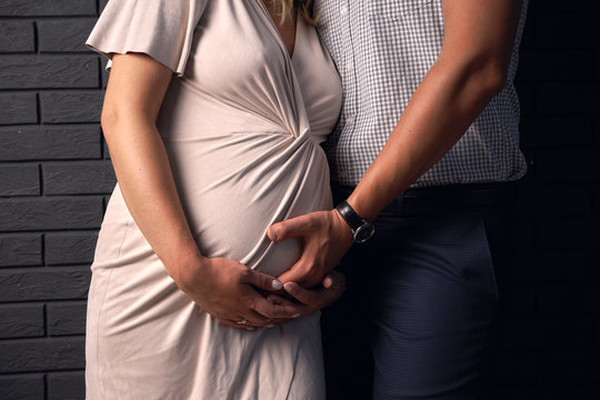 man and woman put their hands to their stomach and listen to how their child is there