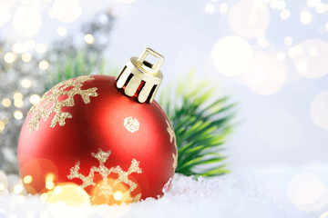 Christmas red ball on snow with golden stars on blue background.