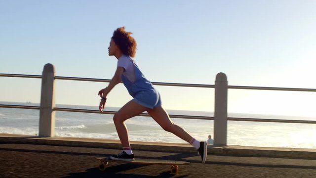 Girl longboarding riding skating enjoying sunshine and being by the ocean
