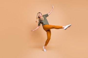 Fototapeta na wymiar Full length body size turned photo of cheerful positive cute charming nice mature energetic woman in yellow green pants trousers expressing excitement om face isolated pastel beige color background