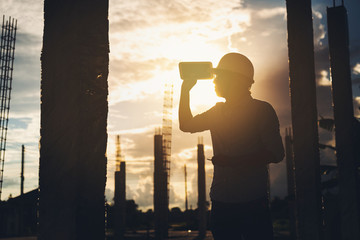 Fototapeta premium silhouette Male architect inspecting building house construction worker at development site