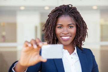 Happy successful businesswoman showing badge. Young African American business woman holding blank card, looking at camera, smiling. Introduction concept