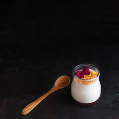 Natural yogurt with strawberry jam accompanied by raspberries and cereals