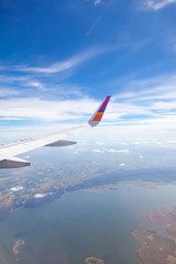 Aircraft Wing on blue sky and white clouds background.