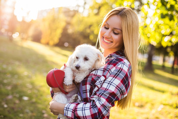 Beautiful woman spending time with her Maltese dog outdoor.	