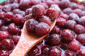 Red cherry with sugar and wooden spoon