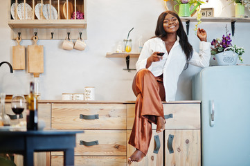 Afro american woman drinking wine in kitchen at her romantic date.