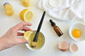 Preparing acne facial mask with natural ingredients, lemon, honey, egg white, tea tree oil, top view.
