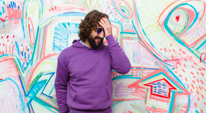 young bearded crazy man laughing and slapping forehead like saying d&sbquo;&Auml;&ocirc;oh! I forgot or that was a stupid mistake against graffiti wall