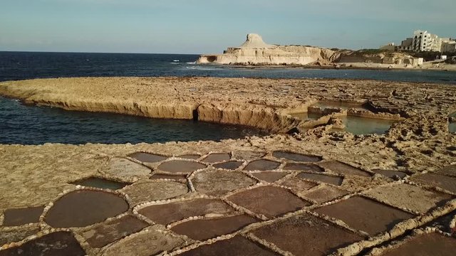 Aerial view of the salt pans at Xwejni bay, Gozo, Malta.Tilt up to reveal bay and hill.