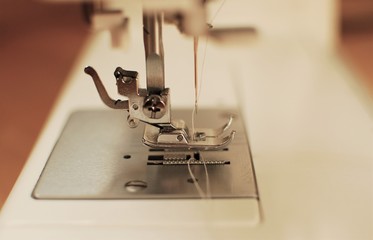 Close-up domestic sewing machine with threaded needle, ready to sew.