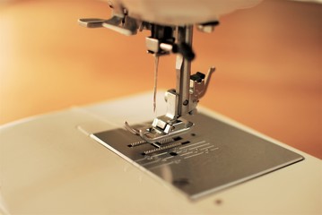 Close-up domestic sewing machine with threaded needle, ready to sew.