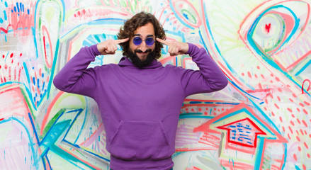 young bearded crazy man with a serious and concentrated look, brainstorming and thinking about a challenging problem against graffiti wall