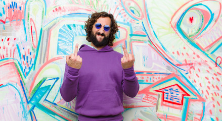 young bearded crazy man feeling provocative, aggressive and obscene, flipping the middle finger,...