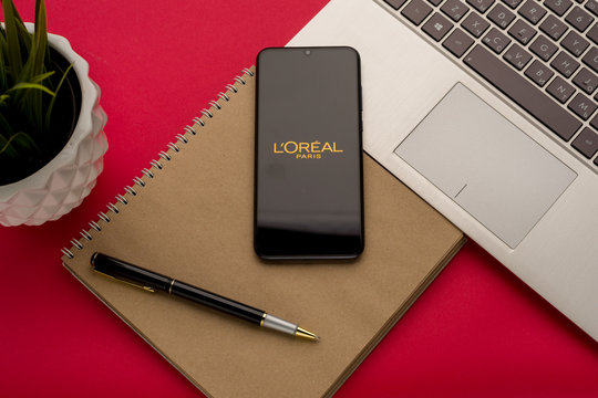 Tula, Russia - october 19, 2019: LOreal Group displayed on a smartphone near modern laptop on red background