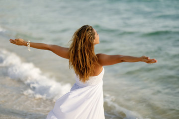 Rear view of carefree woman with arms outstretched at the shore.