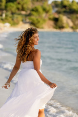Fototapeta na wymiar Playful woman in white dress having fun at the beach.