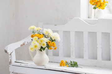 yellow chrysanthemums in jug on old  white wooden bench