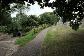Fototapeta na wymiar Typically designed English cemetery showing a path leading to an out of view church.