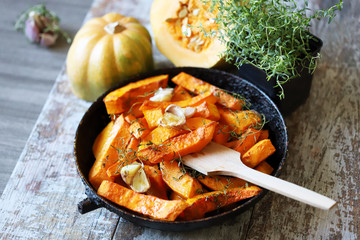 Selective focus. Baked pumpkin with herbs and garlic. Autumn dish. Thanksgiving vegan dinner.