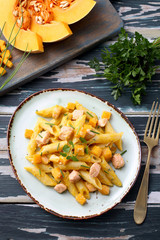 cibo tradizionale mediterraneo pasta zucca gialla e salmone su tavolo verde rustico