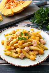 cibo tradizionale mediterraneo pasta zucca gialla e salmone su tavolo verde rustico