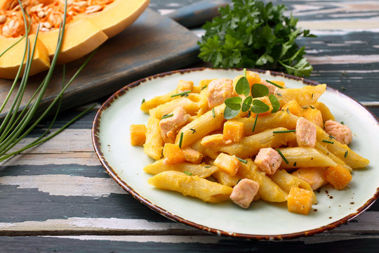 cibo tradizionale mediterraneo pasta zucca gialla e salmone su tavolo verde rustico