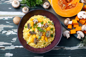 risotto con zucca gialla e funghi su tavolo di cucina rustico verde