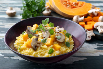 risotto con zucca gialla e funghi su tavolo di cucina rustico verde