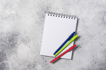 Open blank notebook with colorful pens on the table