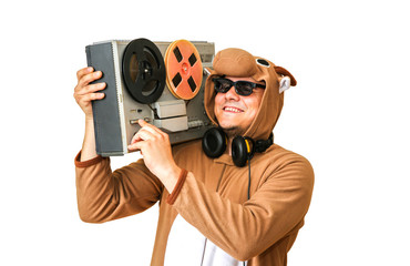 Man in cosplay costume of a cow with reel tape recorder isolated on white background. Guy in the animal pyjamas sleepwear. Funny photo with party ideas. Disco retro music.