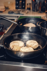 Pancakes from boiled potatoes and cottage cheese are fried in a pan in a cafe. Close up