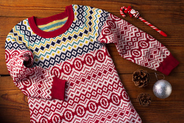 Cute knit winter sweater with colorful ornaments, Christmas decorations, pine cones and Santa lollipop.Flatlay,top view.