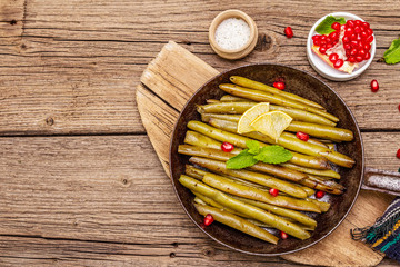 Baked green bean in pan with sesame seeds, pomegranate, mint and lemon